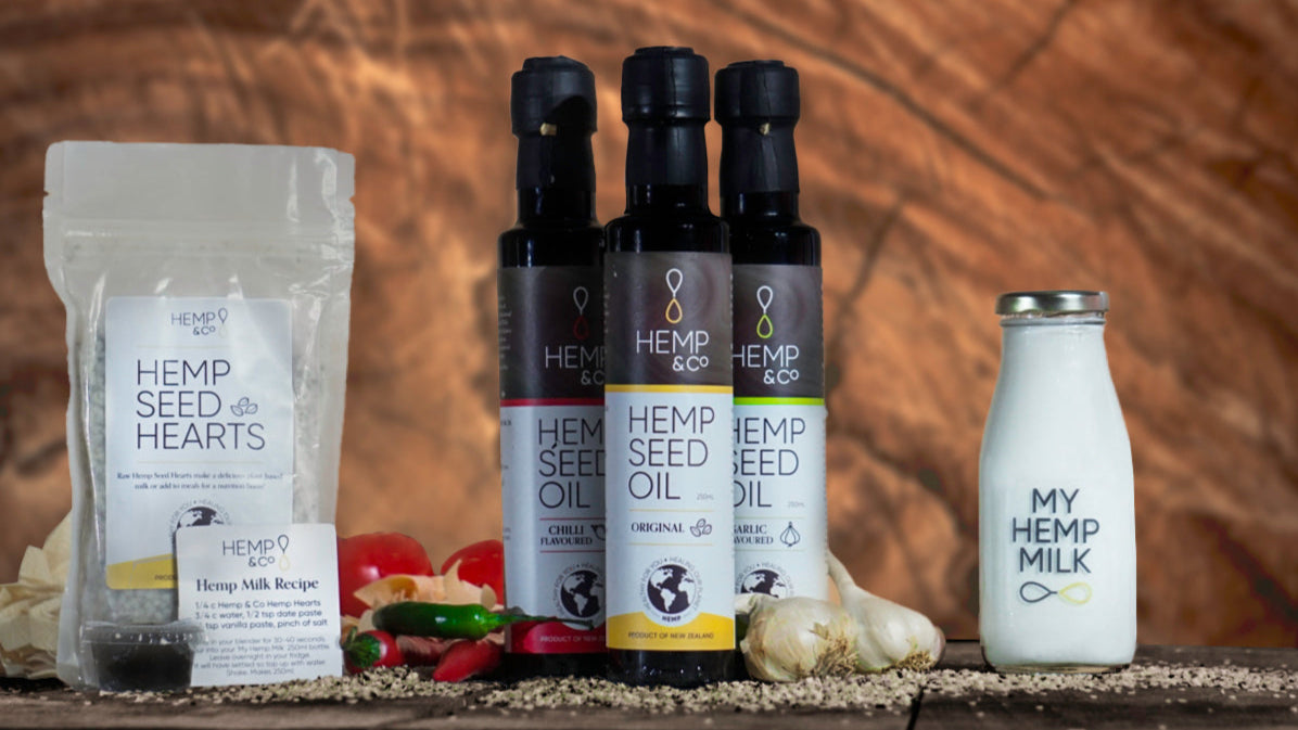 Assorted hemp products including a bag, bottles, and a bottle of milk on a wooden surface.