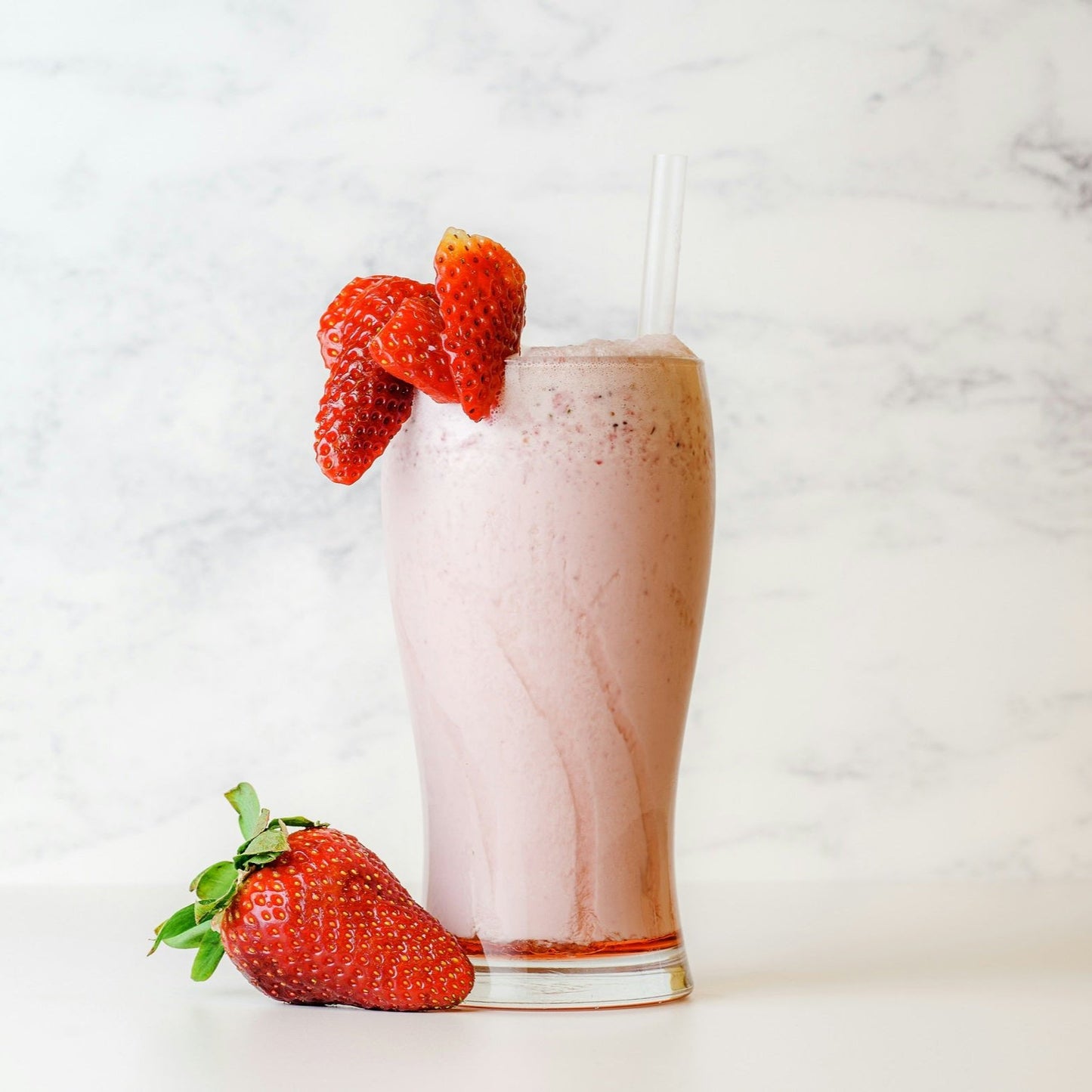 Strawberry milkshake in a glass jar with fresh strawberries as decoration